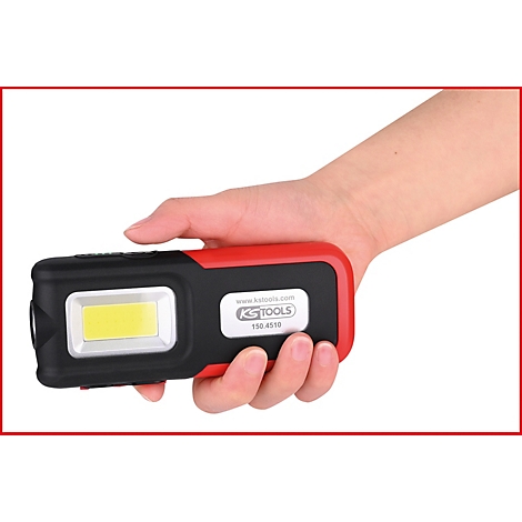 Een hand houdt een zwart-rode LED-werklamp vast. Op de lamp staat een bedrijfslogo en de naam "KS TOOLS".
